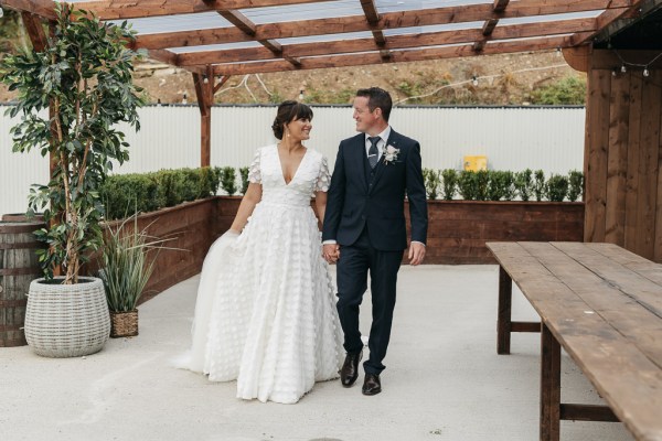 Bride and groom holding hands walking looking at each other