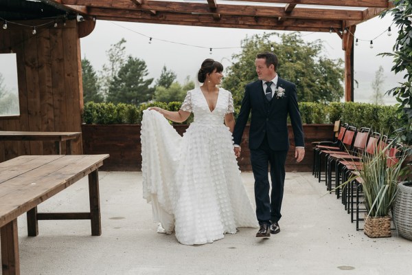 Bride and groom holding hands walking looking at each other