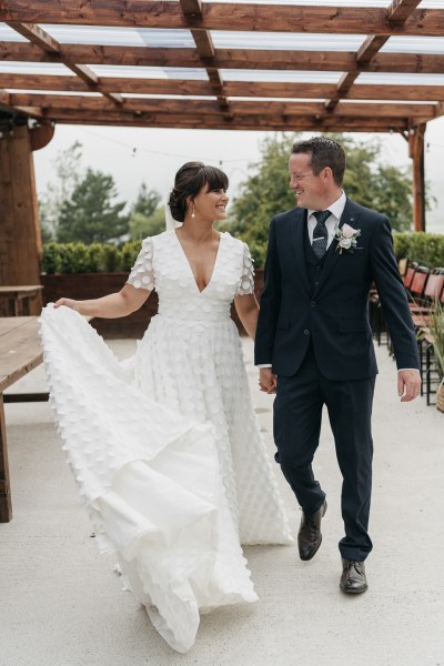 Bride and groom holding hands walking looking at each other