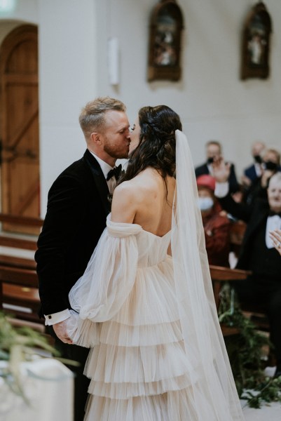 Bride and groom kiss at alter