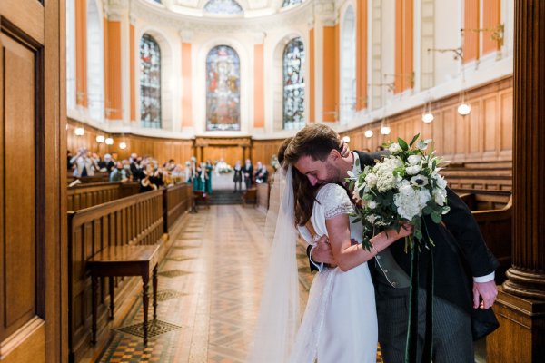 Bride and groom just wed hug after wedding ceremony flowers