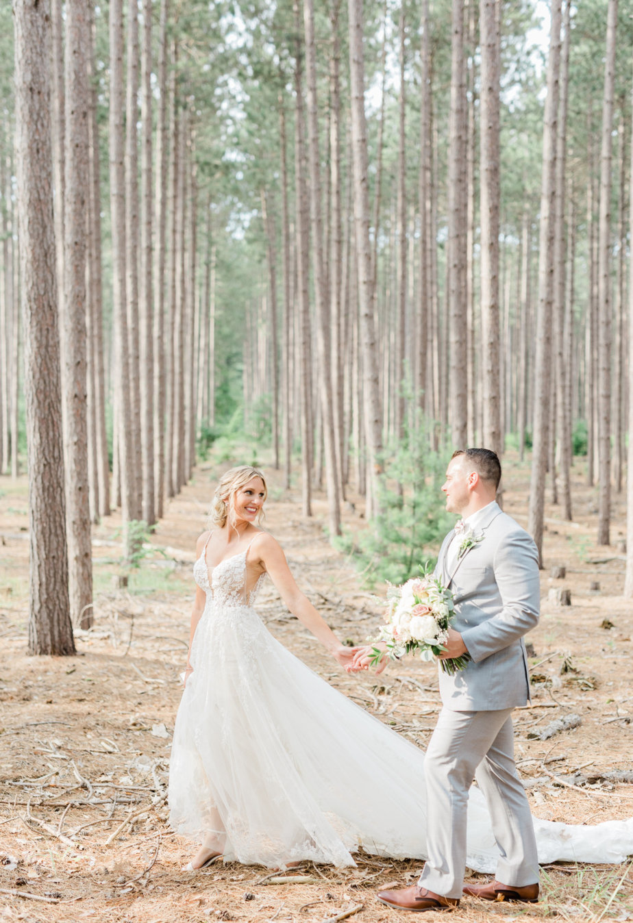 Bride and groom on their own embracing in forest train dress gown holding hands walking