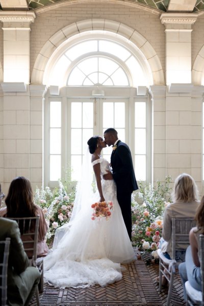 bride and groom at the alter guests wedding kiss