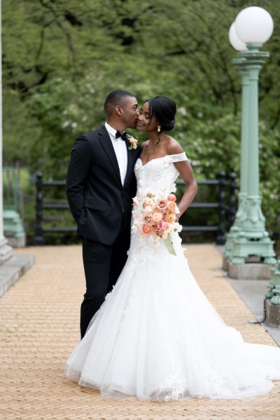 bride and groom holding flowers bouquet kiss