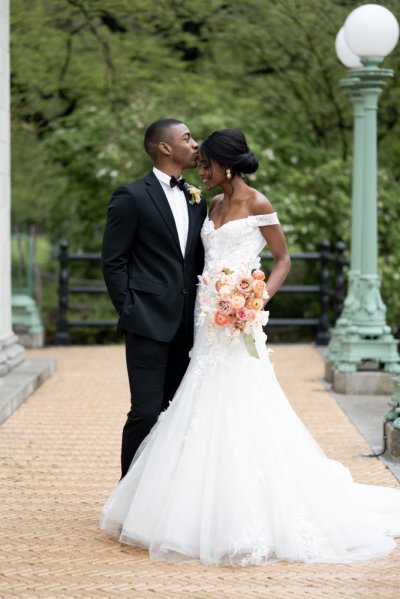 bride and groom holding flowers bouquet kiss