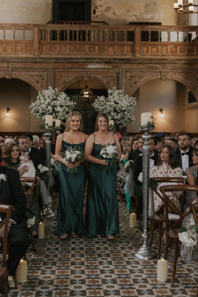 Bridesmaids holding flowers walking down the aisle