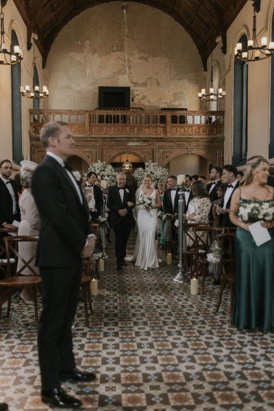 Father walking daughter bride down the aisle groom guests