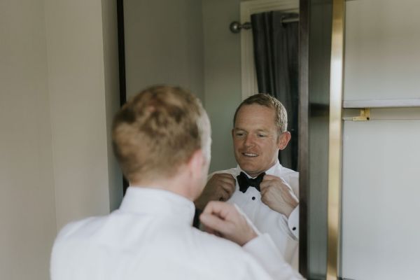 Groom looking in mirror getting ready