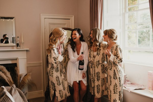 Bride popping champagne with bridesmaids