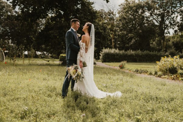 Bride groom embrace earrings veil flowers field grass