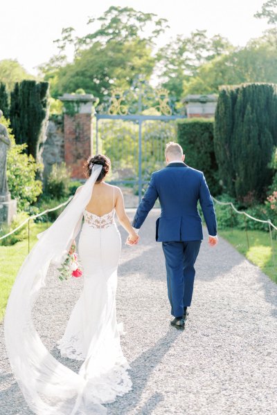 Bride groom exterior veil garden holding hands flowers bouquet