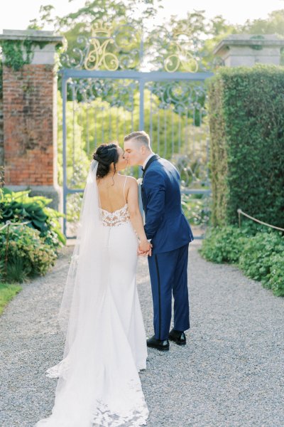 Bride groom exterior veil garden holding hands flowers bouquet kiss