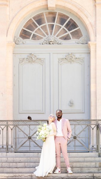 Bride groom pose outside gate door bouquet of flowers