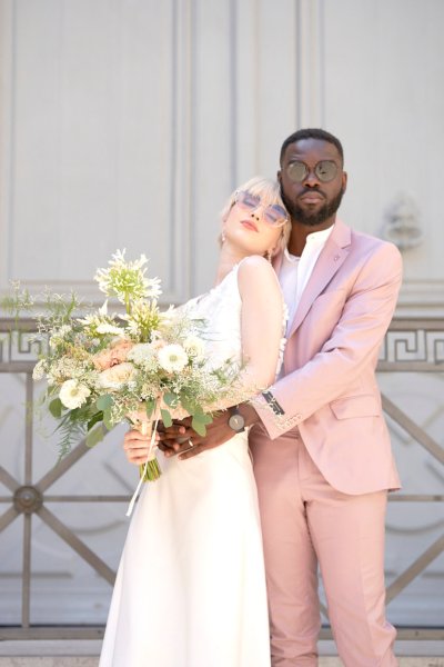 Bride groom pose outside gate door bouquet of flowers