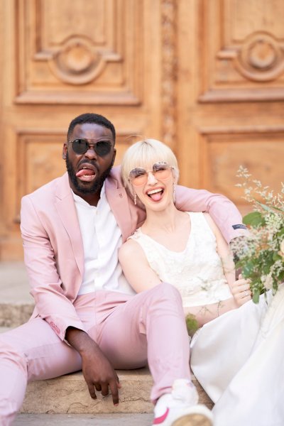 Groom bride sitting against wooden door bouquet flowers