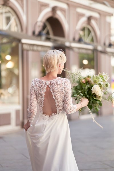 Bride wedding dress lace on her own street style sunglasses glasses bouquet flowers back of dress