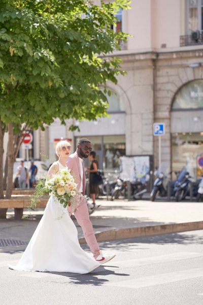 Bride groom pink suit on street holding hands flowers