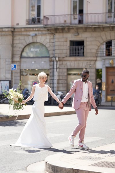 Bride groom pink suit on street holding hands flowers