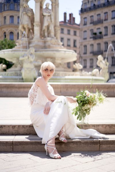 Bride with glasses on at fountain flowers bouquet