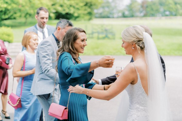 Laughing guests with bride hug embrace