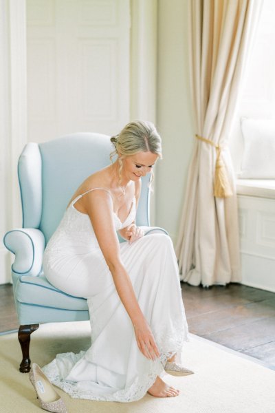 Bride putting on wedding shoes dress getting ready