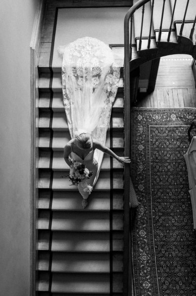 Bride makes her way to ceremony down the stairs black and white