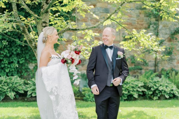 first look Bride holding roses pink red and groom in garden