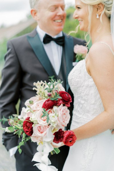 Close up of bow tie groom bride red pink flowers