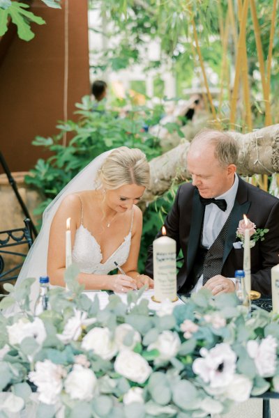 Bride and groom sitting signing paper candles