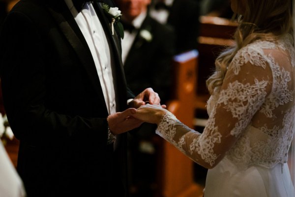 Bride groom alter church guests priest putting rings on fingers