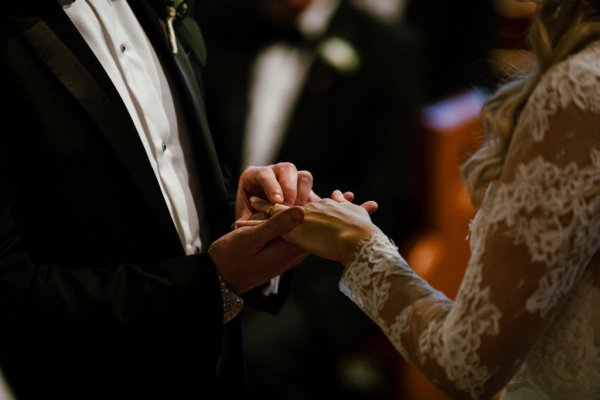 Bride groom alter church guests priest putting rings on fingers