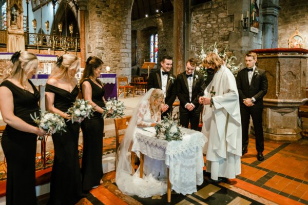 Bride veil groom signing papers church bridesmaids