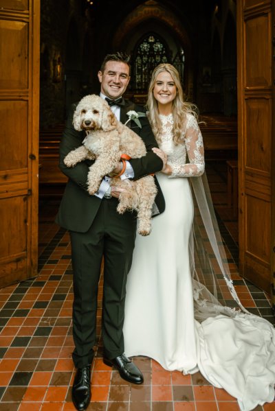 Bride groom hold dog outside church