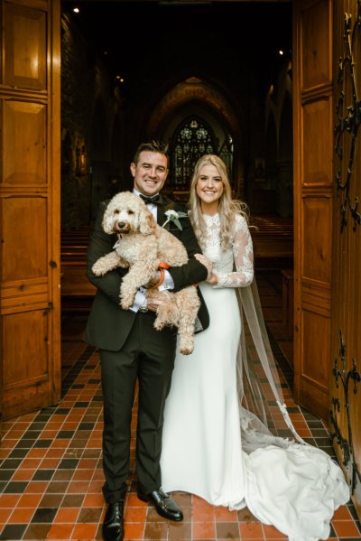 Bride groom hold dog outside church