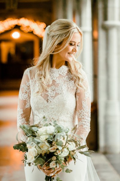 Bride on her own lace bridal gown dress smiling flowers bouquet