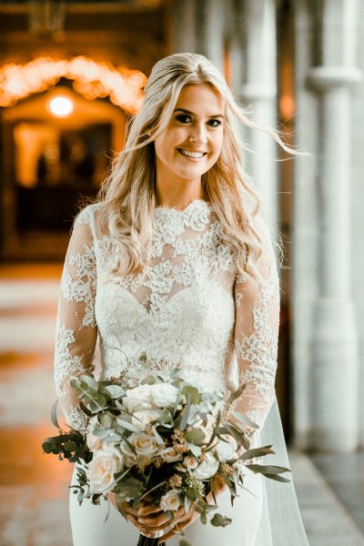 Bride on her own lace bridal gown dress smiling flowers bouquet