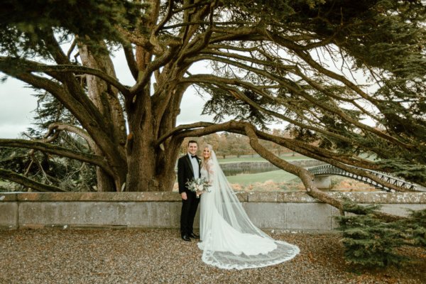 Bride groom exterior forest park long train flowers bouquet