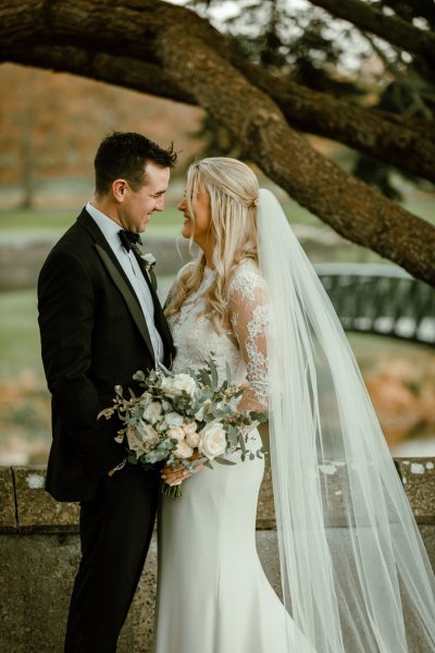 Bride groom exterior forest park long train flowers bouquet