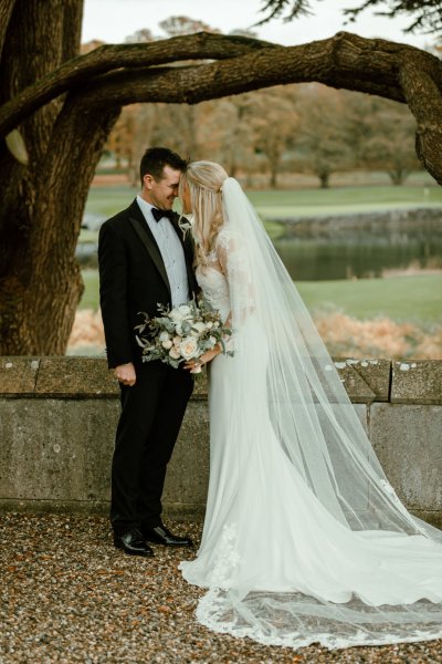 Bride groom exterior forest park long train flowers bouquet