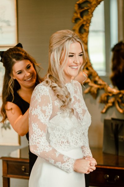 Bridesmaids helping bride get ready smiling laughing