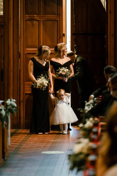 Little flower girl wearing white dress guests bouquet flowers