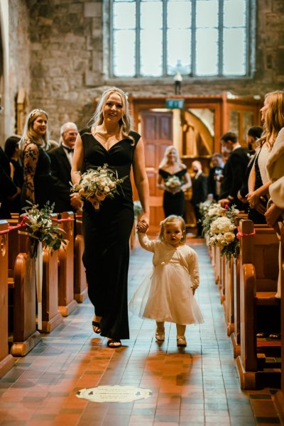 Little flower girl wearing white dress guests bouquet flowers