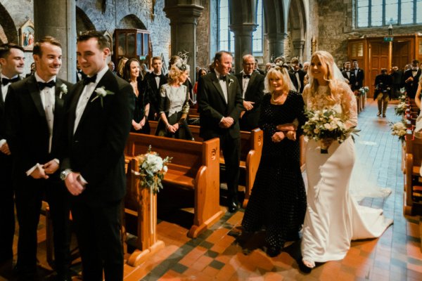 Mother walking bride down the aisle church guests