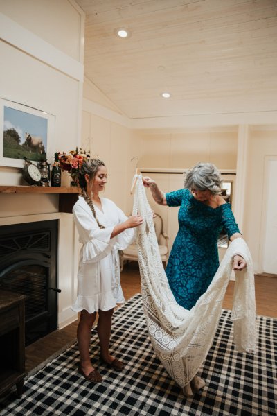 Bridesmaid helping bride button up lace dress long train