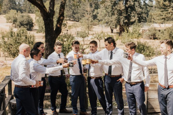 Groom groomsmen cheers suit tie exterior park