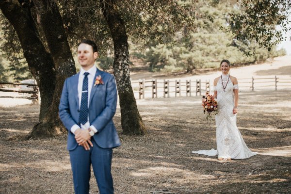 first look Bride groom forest park tree sunshine bouquet flowers hay field standing behind