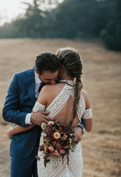 Bride and groom embracing flowers rose bouquet park forest