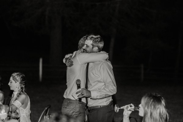 Black and white guests hugging groom