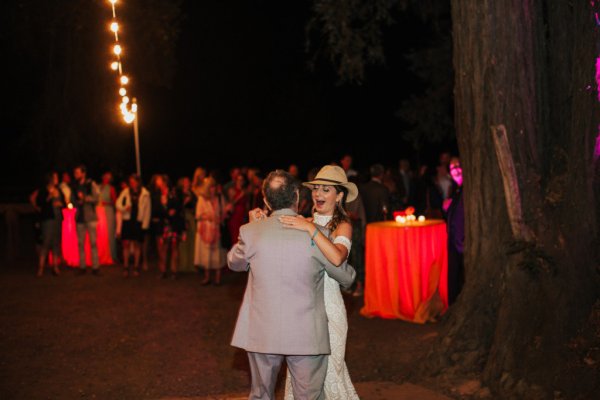 Bride wearing straw hat dancing with dad father