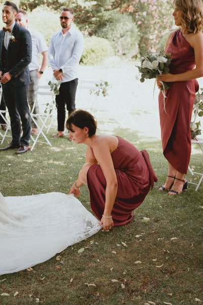 Bridesmaid helps bride with train dress